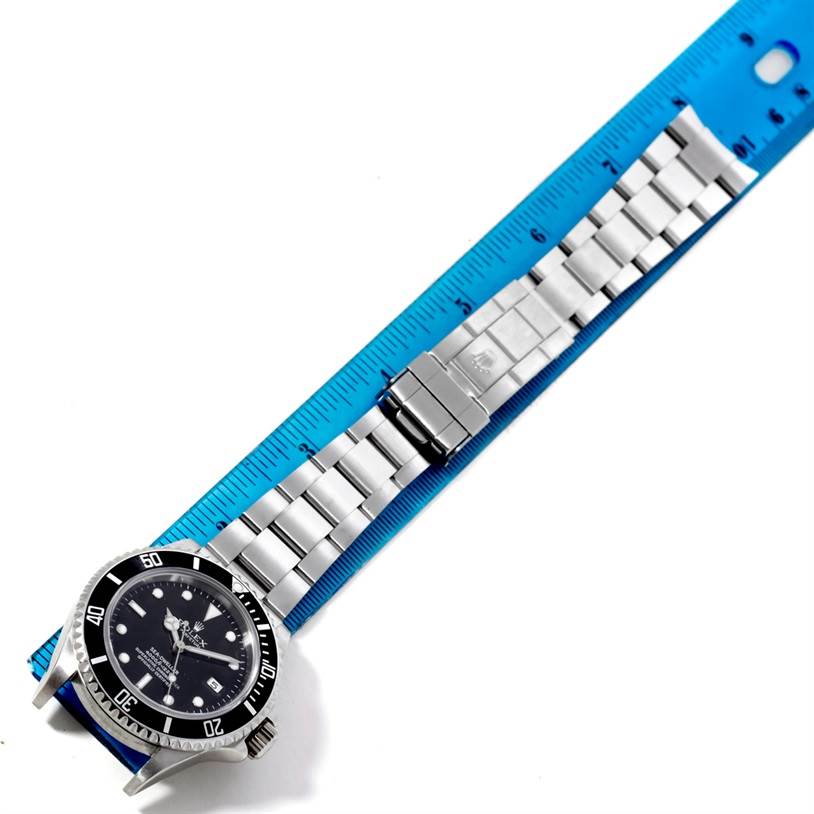 This image shows a full view of the Rolex Sea-Dweller 16600 Men
s Stainless Steel Black Dial 16600 Men
s Stainless Steel Black Dial watch laying flat with its stainless steel bracelet extended and measured by a blue ruler.
