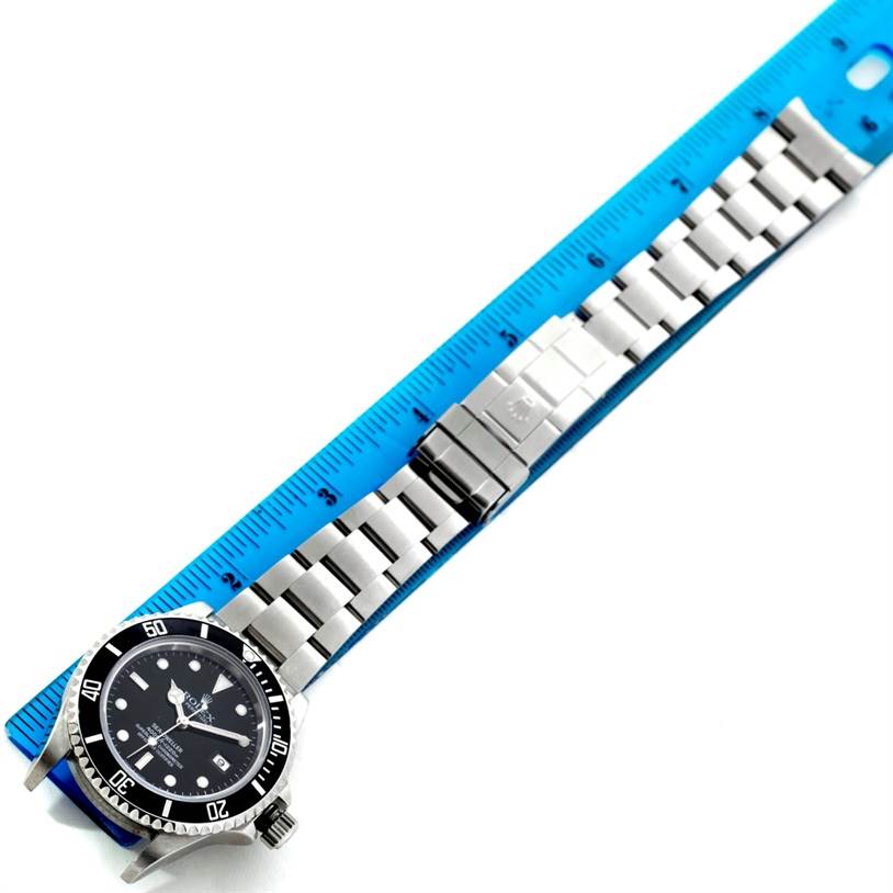 This image shows a top-down view of a Rolex Sea-Dweller 16600 Men's Stainless Steel Black Dial 16600 Men's Stainless Steel Black Dial watch with its metal bracelet aligned alongside a blue ruler.