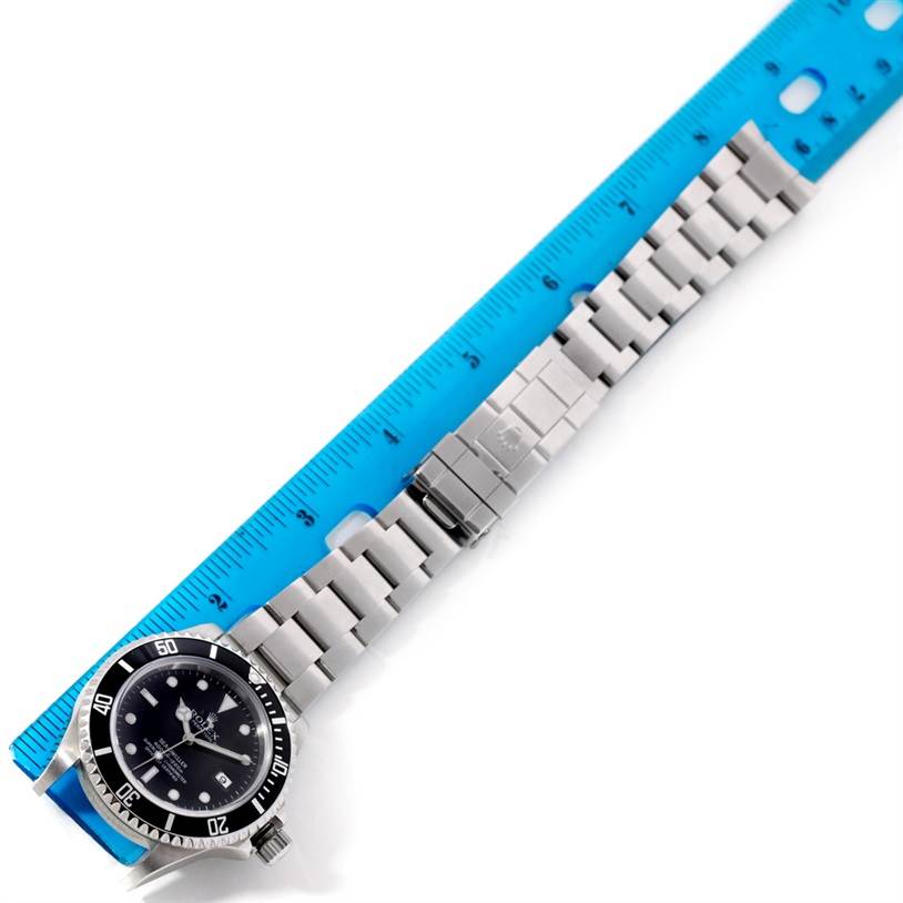 The image shows a top-down view of a Rolex Sea-Dweller 16600 Men's Stainless Steel Black Dial 16600 Men's Stainless Steel Black Dial watch with its bracelet laid out next to a blue ruler for measuring size.