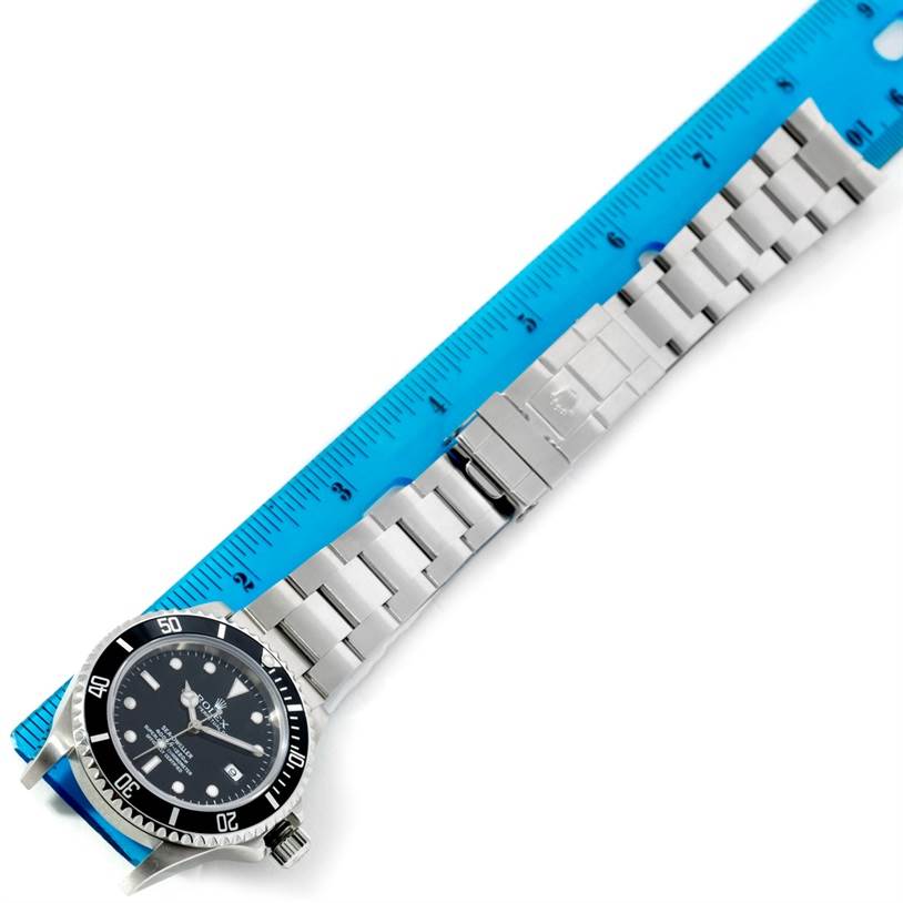 The image shows a Rolex Sea-Dweller 16600 Men
s Stainless Steel Black Dial 16600 Men
s Stainless Steel Black Dial watch laid flat with its stainless steel bracelet extended next to a blue ruler.