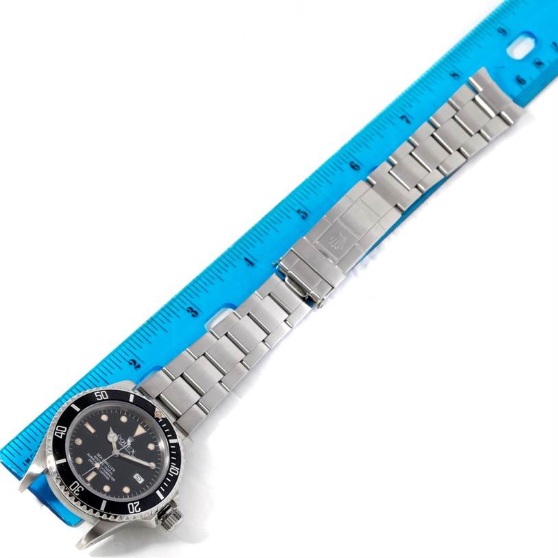 The image shows a Rolex Sea-Dweller 16660 Men's Stainless Steel Black Dial 16660 Men's Stainless Steel Black Dial watch laid flat with the full view of the watch clasp, bracelet, and dial, alongside a blue ruler for scale.