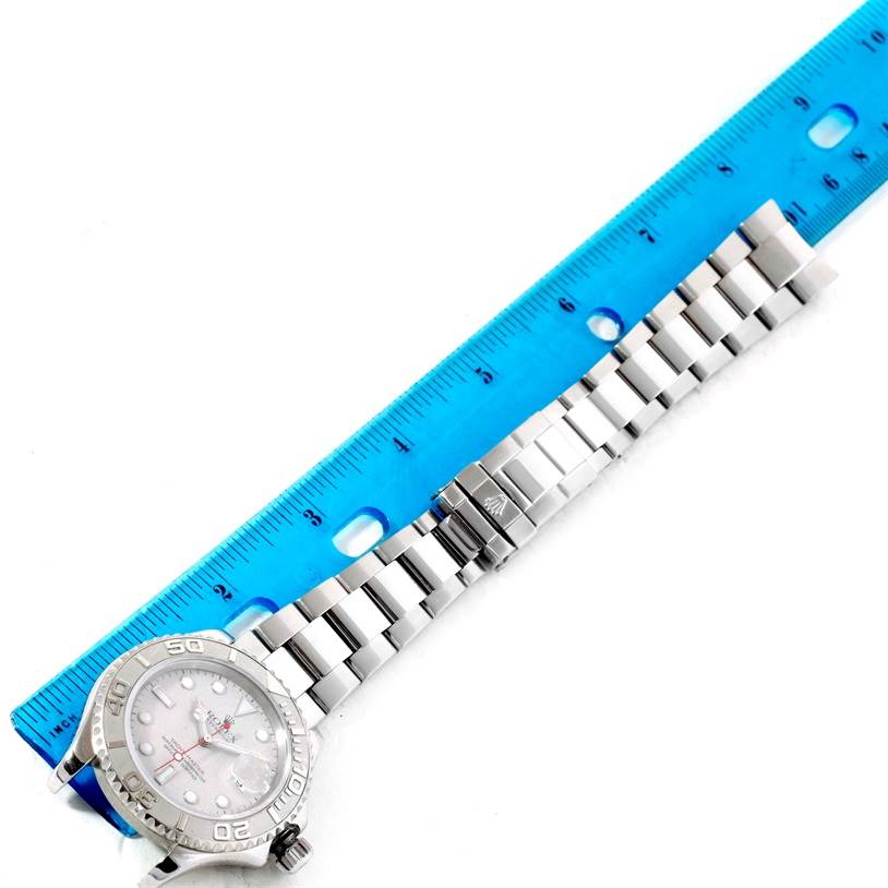 The image shows a top-down view of a Rolex Yacht-Master 16622 Men
s Stainless Steel Silver Dial 16622 Men
s Stainless Steel Silver Dial watch, including its face and metal bracelet, with a ruler adjacent for scale.