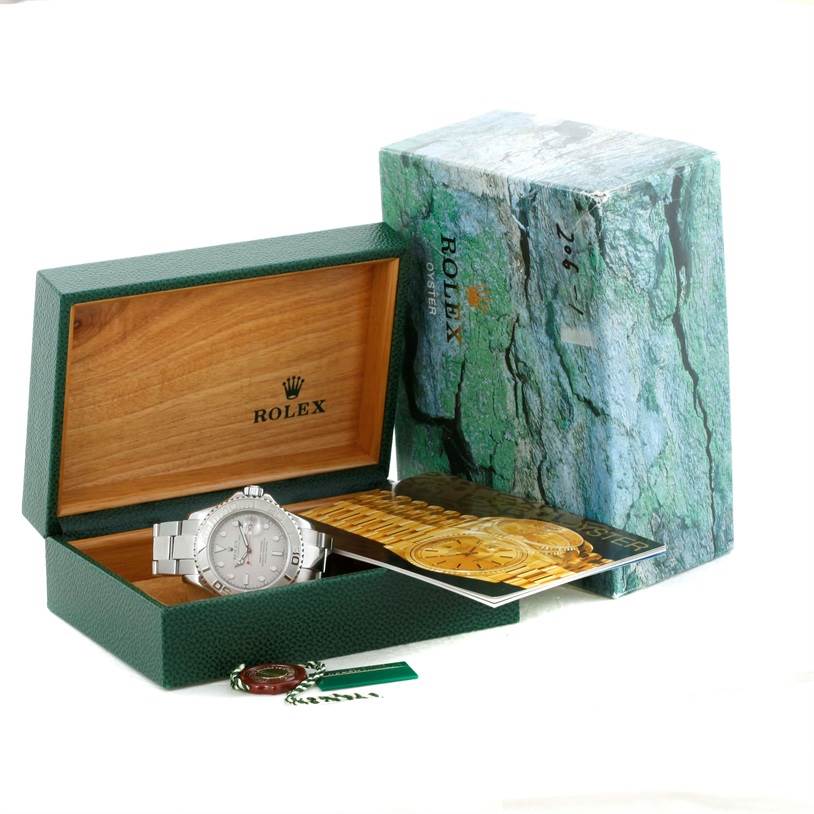The Rolex Yacht-Master 16622 Men's Stainless Steel Silver Dial 16622 Men's Stainless Steel Silver Dial watch is displayed in an open green and wooden box, accompanied by paperwork and a tag.