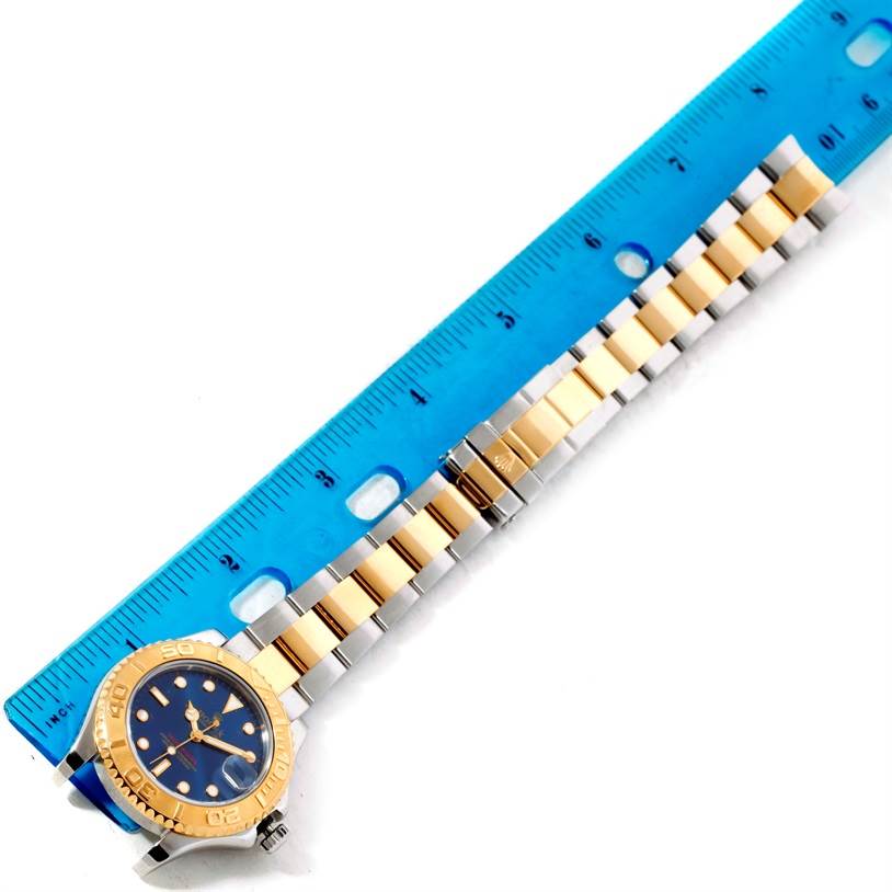 The image shows the Rolex Yacht-Master 68623 Men's Stainless Steel Blue Dial 68623 Men's Stainless Steel Blue Dial watch laid flat with the dial and bracelet displayed next to a blue ruler for scale.