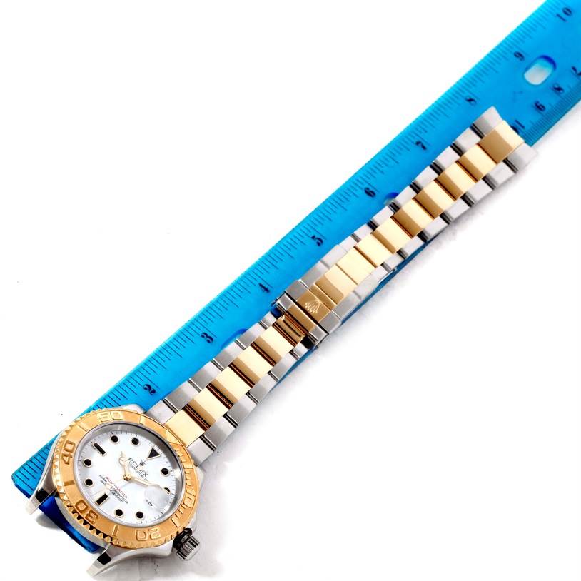 The Rolex Yacht-Master 16623 Men's Stainless Steel White Dial 16623 Men's Stainless Steel White Dial watch is displayed with a full view of the face and band next to a blue ruler for measurement.