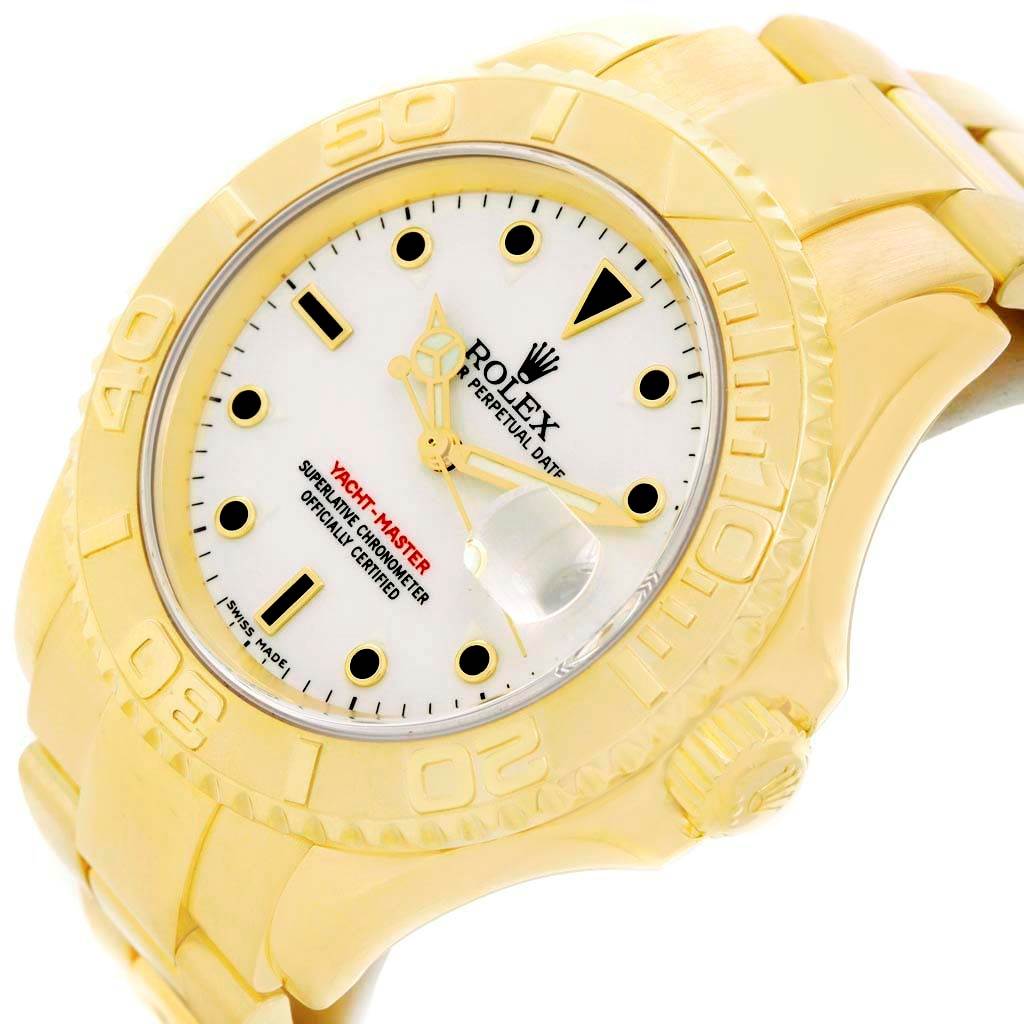The image shows a close-up view of a Rolex Yacht-Master 16628 Men's Yellow Gold White Dial 16628 Men's Yellow Gold White Dial watch displaying its dial, bezel, and part of the bracelet from an angle.