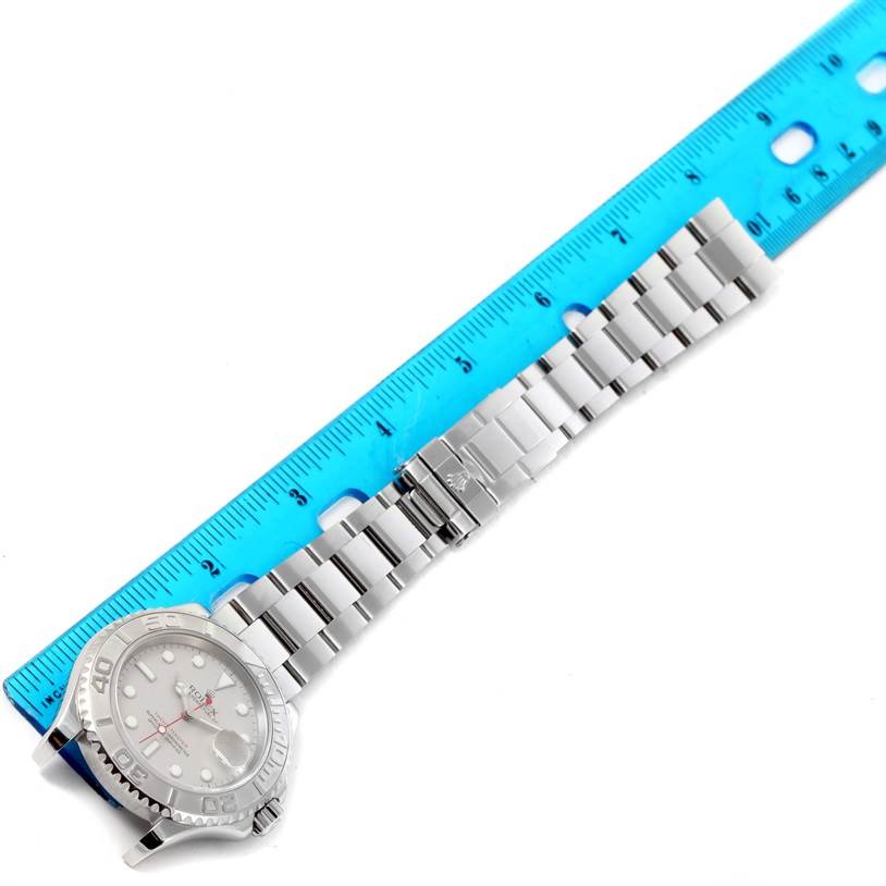 The image shows a Rolex Yacht-Master 16622 Men's Stainless Steel Silver Dial 16622 Men's Stainless Steel Silver Dial watch with its metal bracelet fully extended next to a blue ruler for measurement.