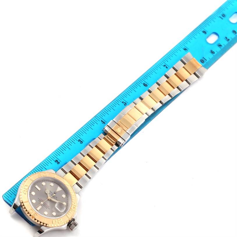 The image shows a Rolex Yacht-Master 16623 Men's Stainless Steel Grey Dial 16623 Men's Stainless Steel Grey Dial watch placed next to a blue ruler, highlighting its two-tone bracelet and dial.