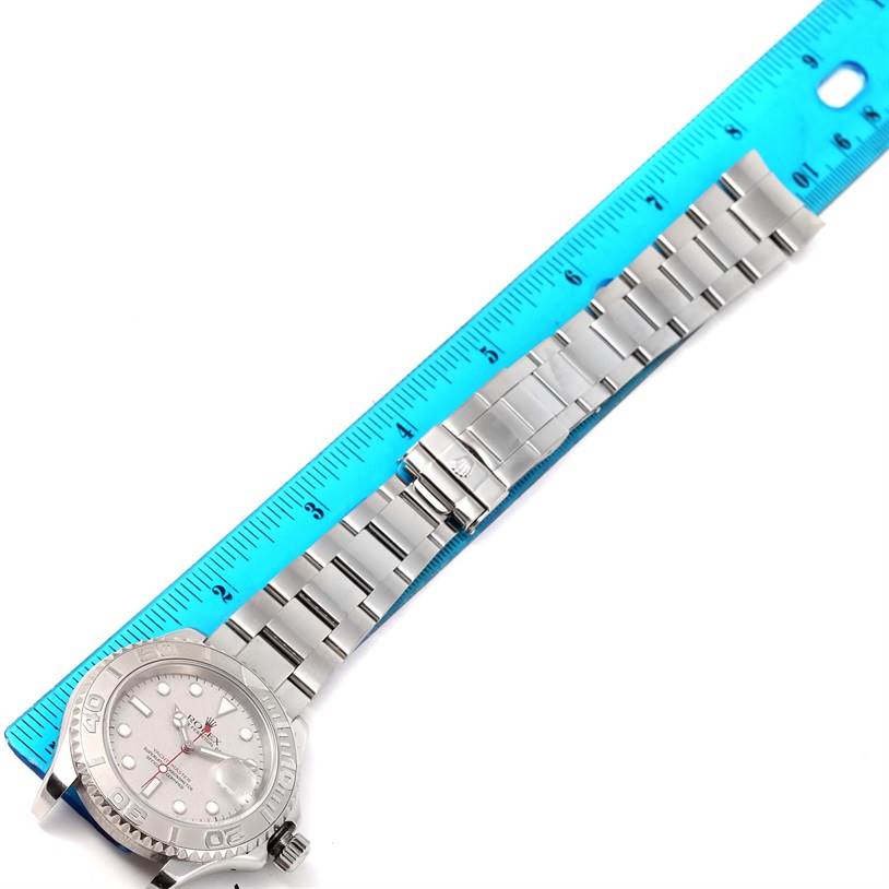 The Rolex Yacht-Master 16622 Men's Stainless Steel Silver Dial 16622 Men's Stainless Steel Silver Dial watch is shown from a top-down angle with the face, bracelet, and clasp visible next to a blue ruler.