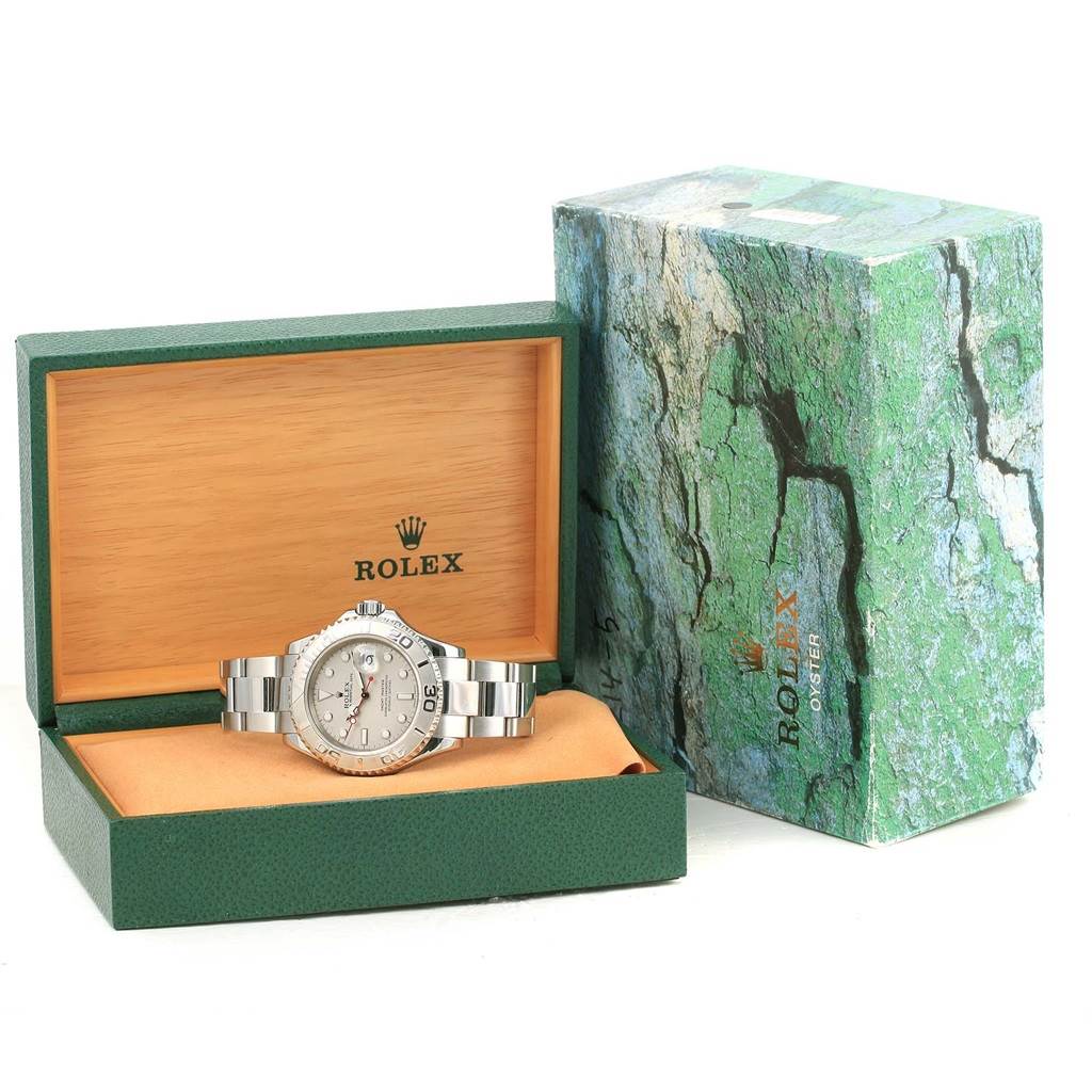This image shows a Rolex Yacht-Master 16622 Men's Stainless Steel Silver Dial 16622 Men's Stainless Steel Silver Dial watch displayed in an open green and wood box with its outer packaging next to it.