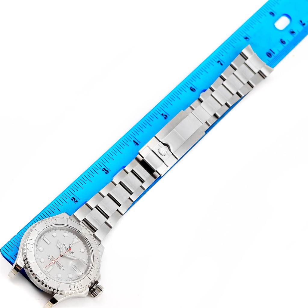 This image shows a top-down view of a Rolex Yacht-Master 116622 Men's Stainless Steel Silver Dial 116622 Men's Stainless Steel Silver Dial watch with its band and face alongside a blue ruler.