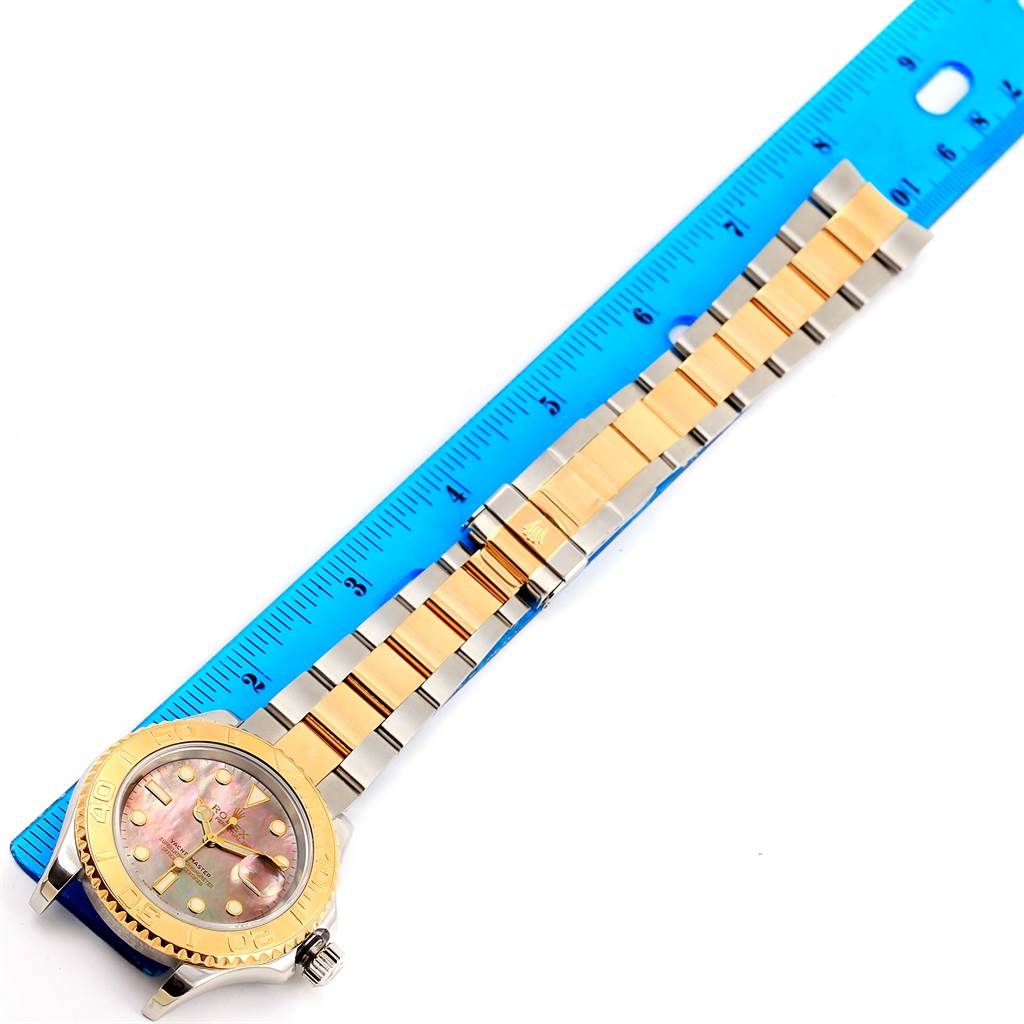 The image shows the full length of a Rolex Yacht-Master 16623 Men's Stainless Steel Mother of Pearl Dial 16623 Men's Stainless Steel Mother of Pearl Dial watch with a gold and silver bracelet, next to a ruler for scale.