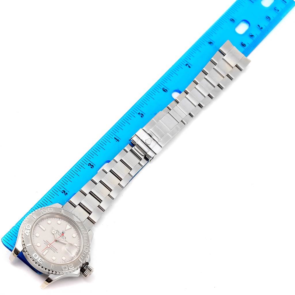 This image shows a Rolex Yacht-Master 16622 Men
s Stainless Steel Silver Dial 16622 Men
s Stainless Steel Silver Dial watch laid flat next to a blue ruler, displaying its face, bezel, and metal bracelet.