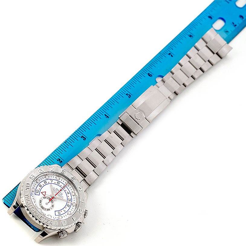 The image shows a Rolex Yacht-Master 116689 Men
s White Gold White Dial 116689 Men
s White Gold White Dial watch laid flat next to a blue ruler, highlighting its bracelet and watch face.