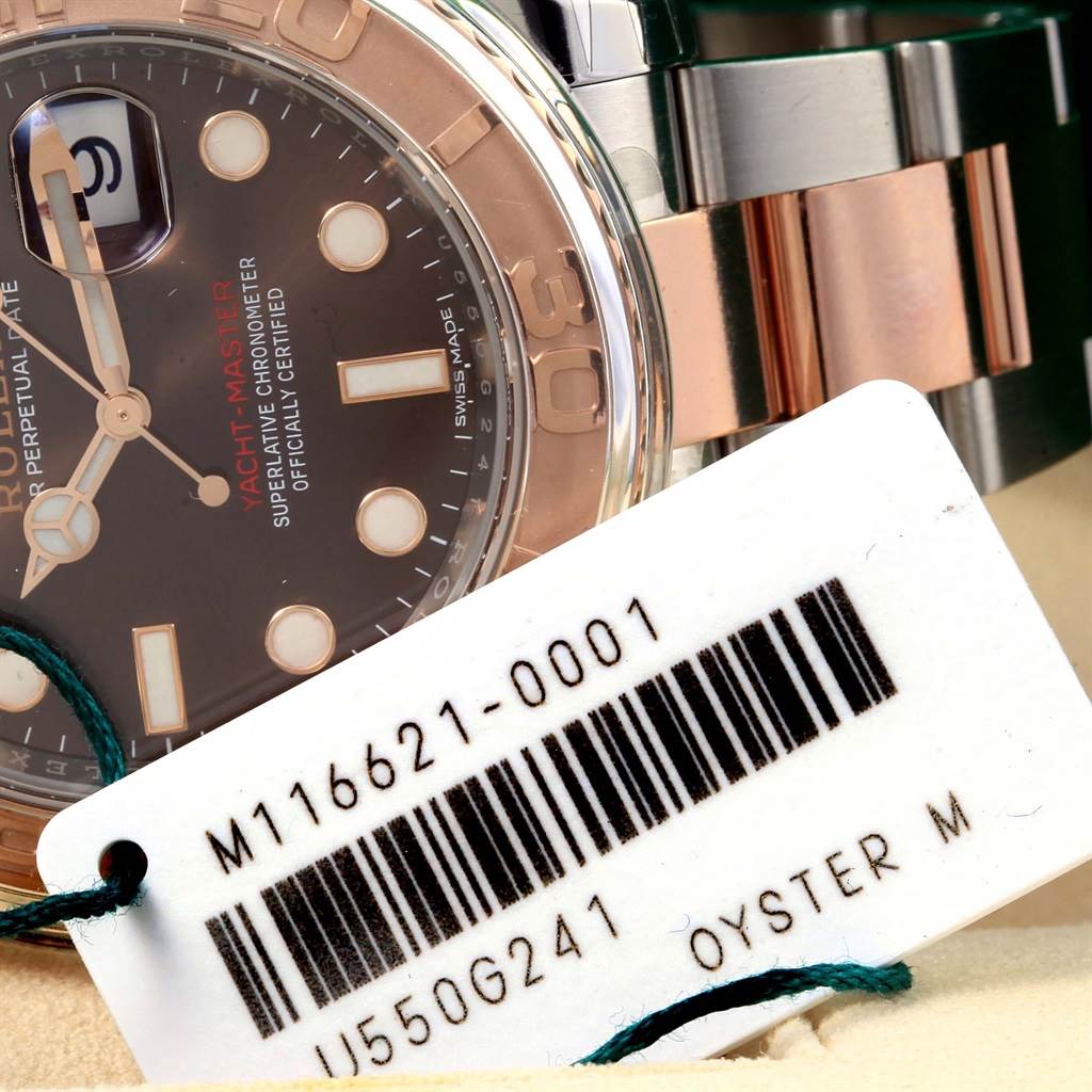 The image shows a close-up of the dial, bezel, and part of the bracelet of a Rolex Yacht-Master 116621 Men's Stainless Steel Brown Dial 116621 Men's Stainless Steel Brown Dial watch with a tag attached.
