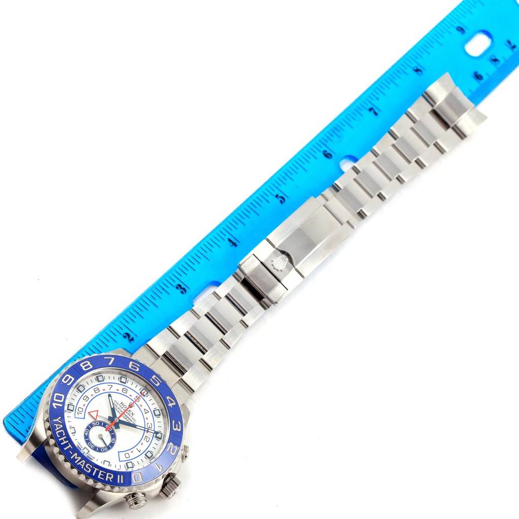 This Rolex Yacht-Master 116680 Men's Stainless Steel White Dial 116680 Men's Stainless Steel White Dial watch is shown from above, displaying the face, bezel, and full metal bracelet alongside a blue ruler.