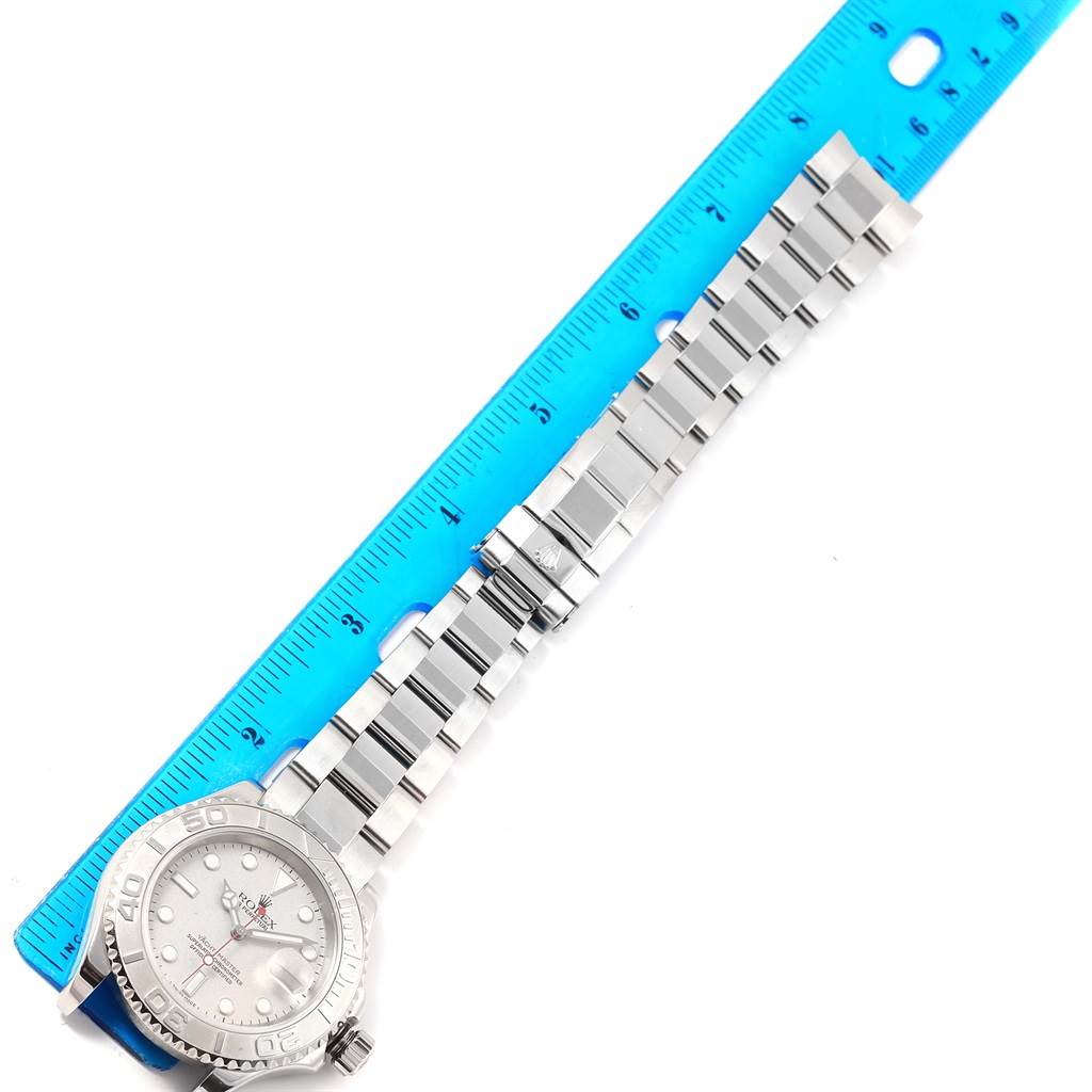 The image shows a top-down view of a Rolex Yacht-Master 16622 Men's Stainless Steel Silver Dial 16622 Men's Stainless Steel Silver Dial watch alongside a blue ruler.