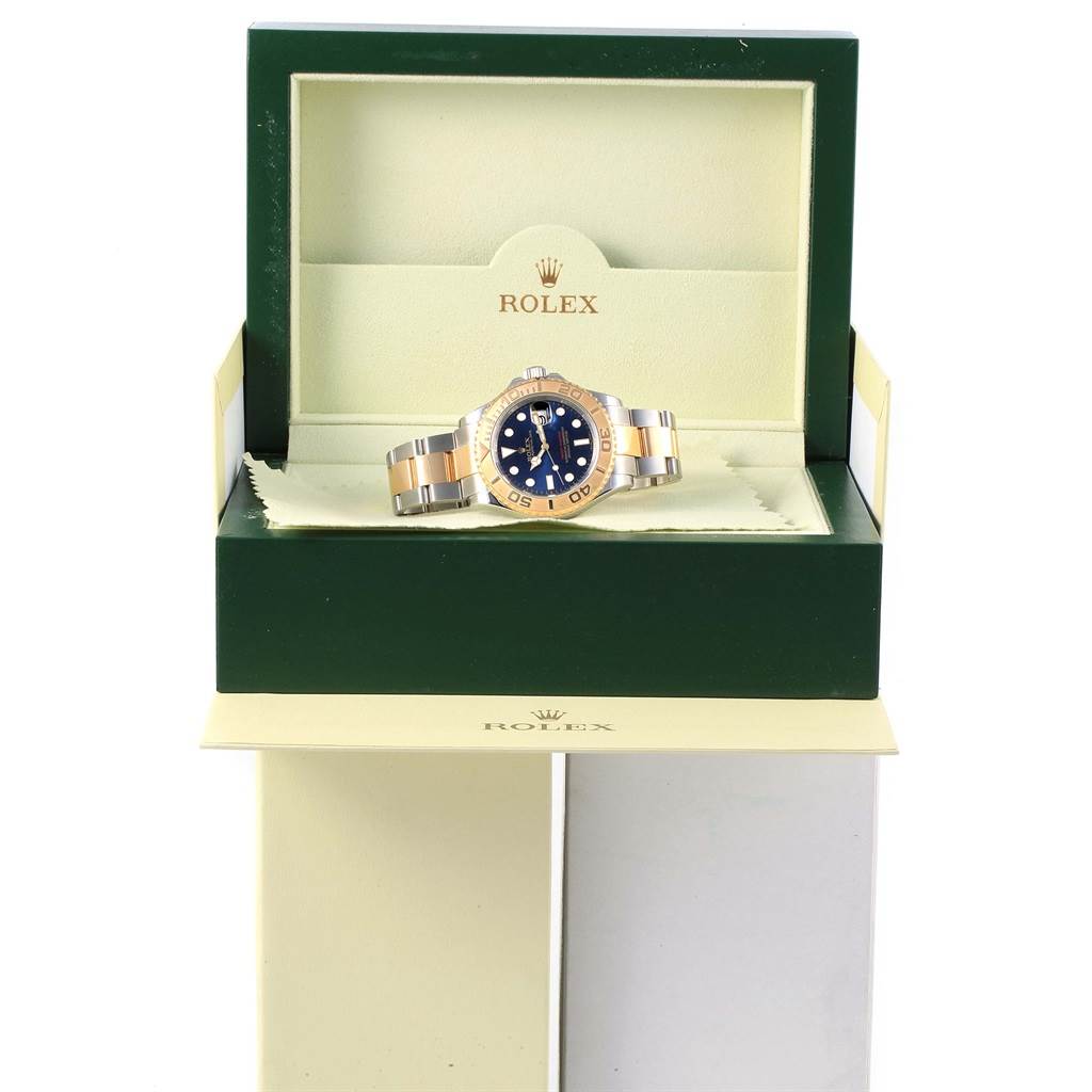 The Rolex Yacht-Master 16623 Men's Stainless Steel Blue Dial 16623 Men's Stainless Steel Blue Dial watch is shown from the front, packaged in an open green and beige box displaying its bezel and bracelet.