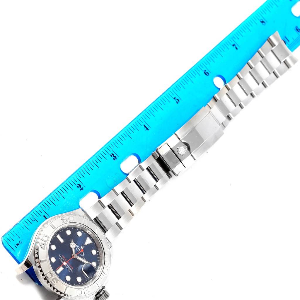 This image shows a side view of a Rolex Yacht-Master 116622 Men's Stainless Steel Blue Dial 116622 Men's Stainless Steel Blue Dial watch laid next to a blue ruler, focusing on the bracelet and clasp.