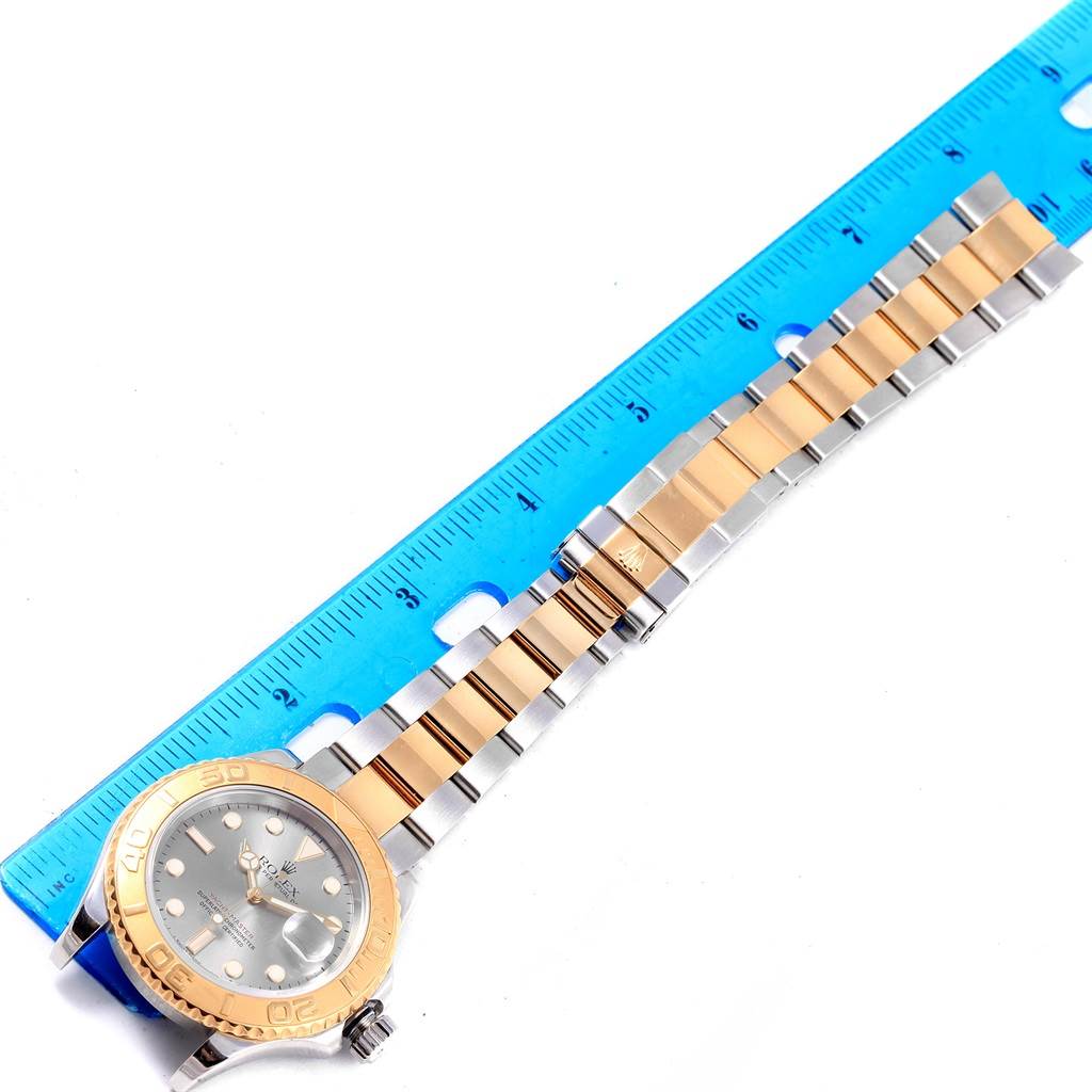 This image shows the Rolex Yacht-Master 16623 Men's Stainless Steel Grey Dial 16623 Men's Stainless Steel Grey Dial watch laid flat with its strap aligned next to a blue ruler for scale.