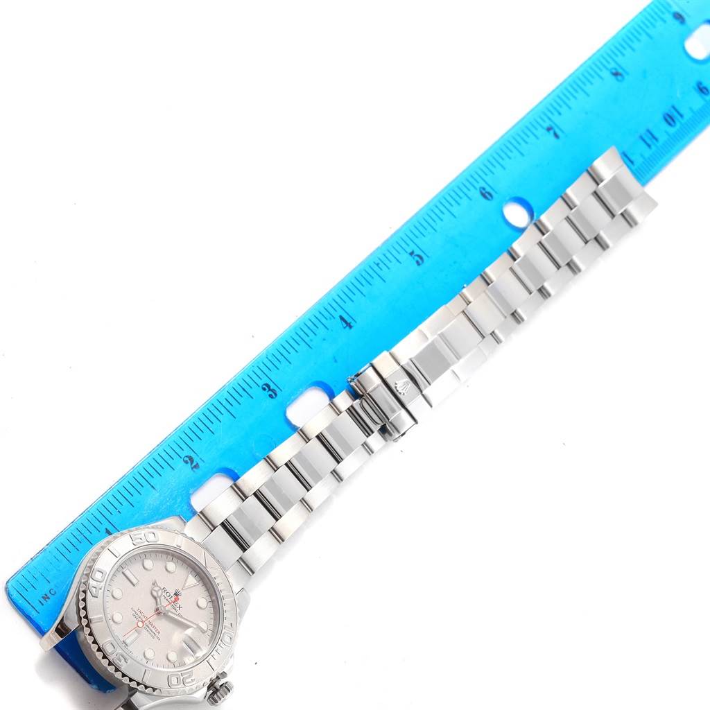 The image shows a Rolex Yacht-Master 168622 Men's Stainless Steel Silver Dial 168622 Men's Stainless Steel Silver Dial watch laid flat beside a blue ruler, displaying the face and full metal bracelet.