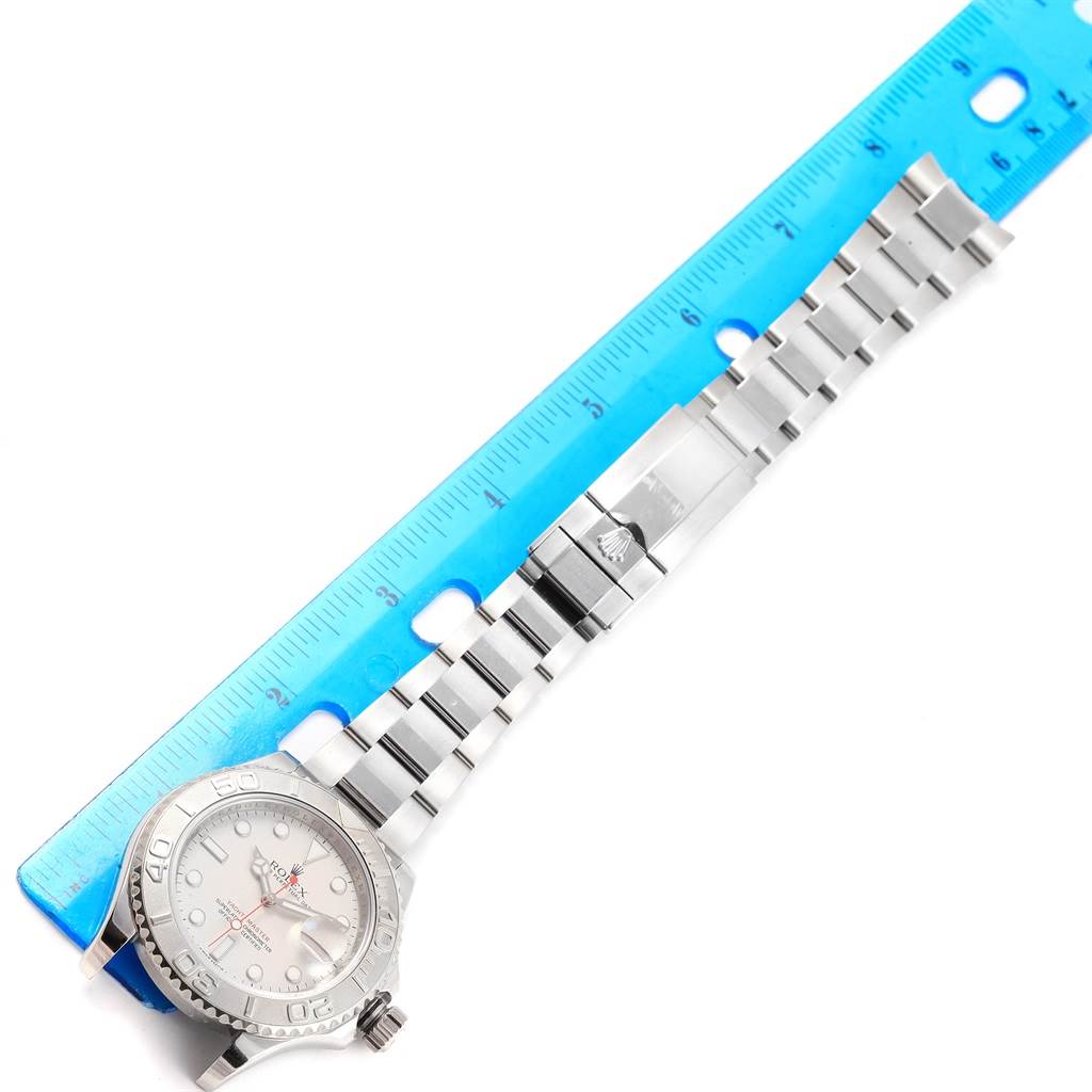 The Rolex Yacht-Master 116622 Men's Stainless Steel Silver Dial 116622 Men's Stainless Steel Silver Dial watch is shown from an overhead angle, displaying the face, bezel, and full bracelet next to a blue ruler.