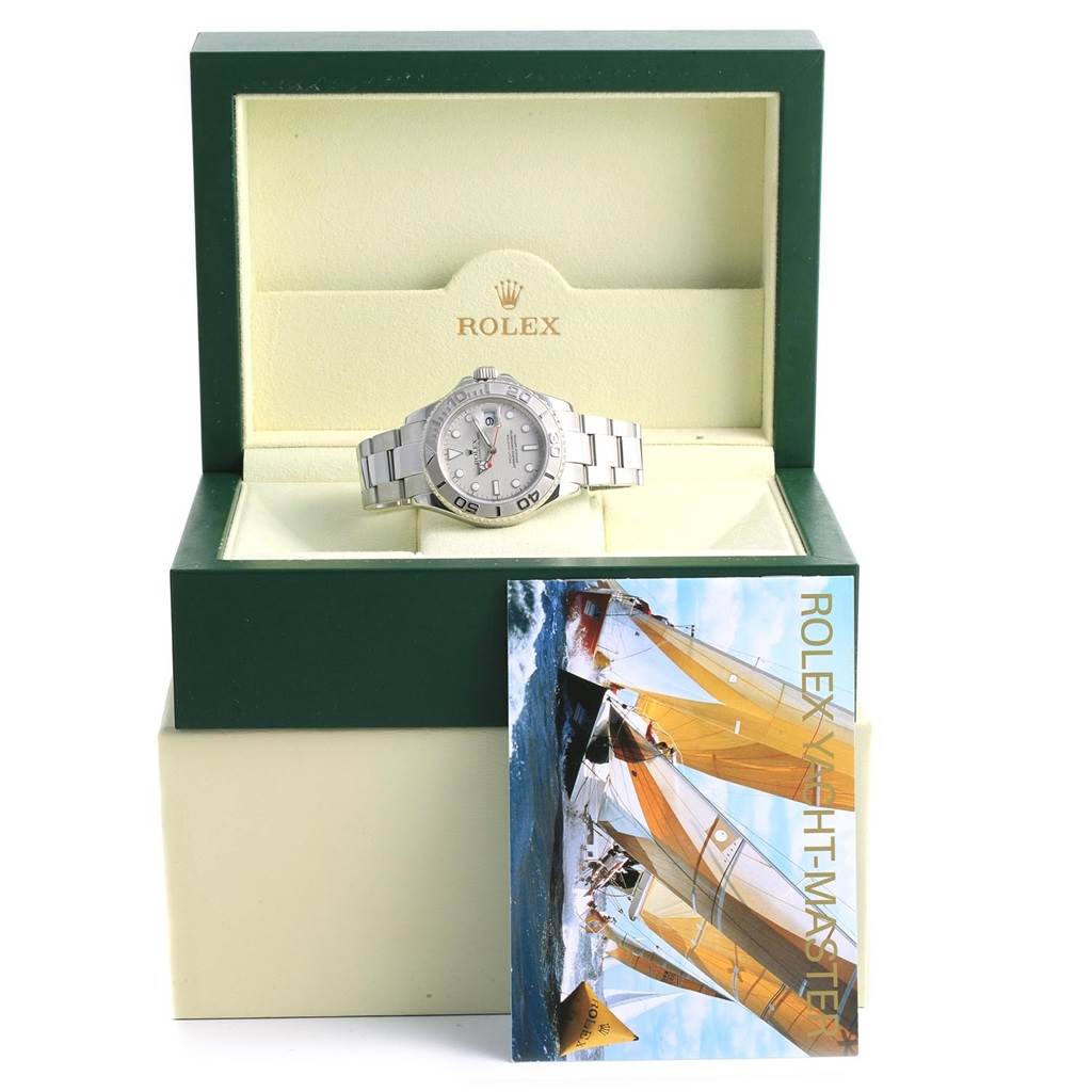 The Rolex Yacht-Master 16622 Men's Stainless Steel Silver Dial 16622 Men's Stainless Steel Silver Dial watch is displayed front and center in an open green and beige box with a leaflet positioned below it.