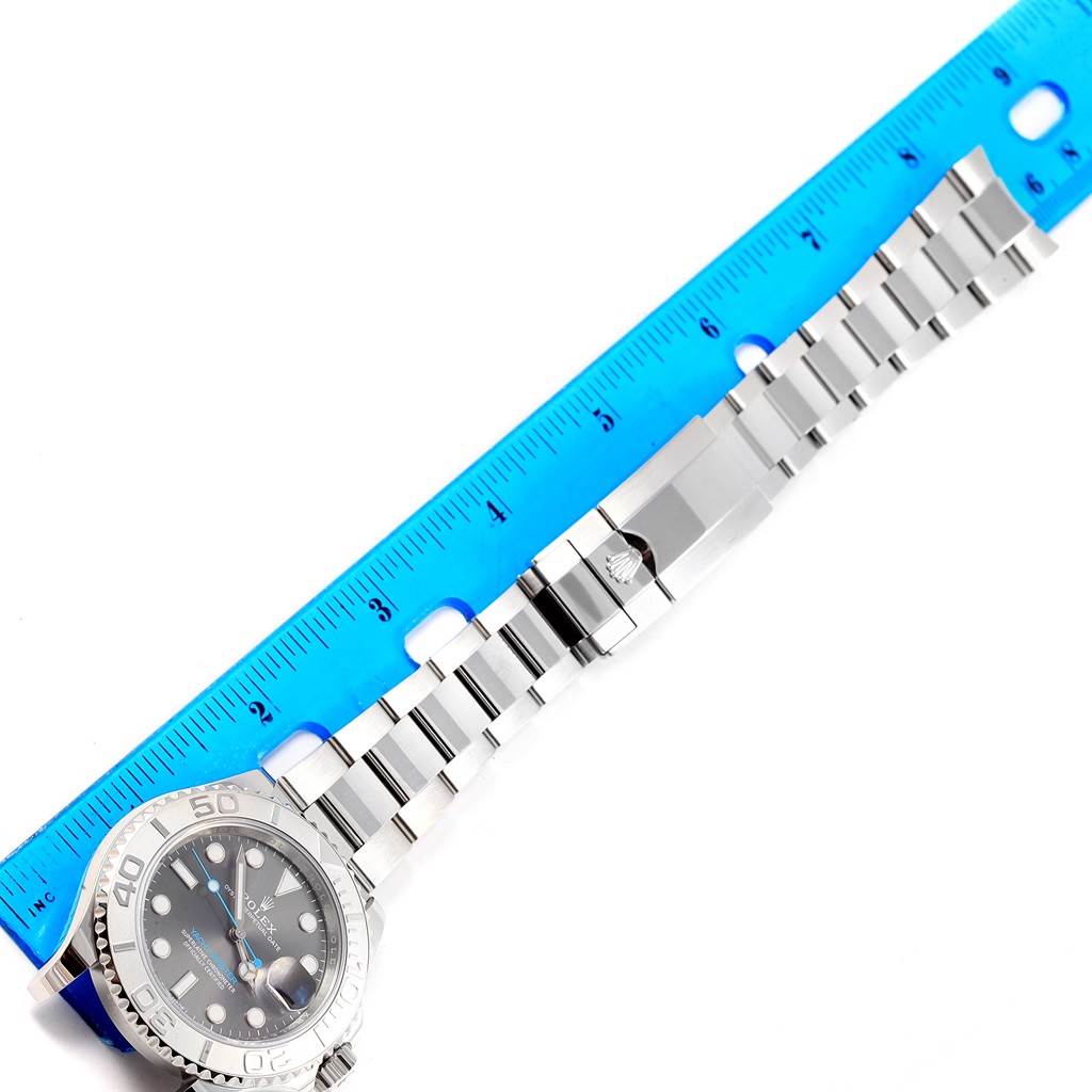 The image shows the Rolex Yacht-Master 116622 Stainless Steel Grey Dial 116622 Stainless Steel Grey Dial watch laid next to a blue ruler, focusing on the bracelet and clasp from a top view.