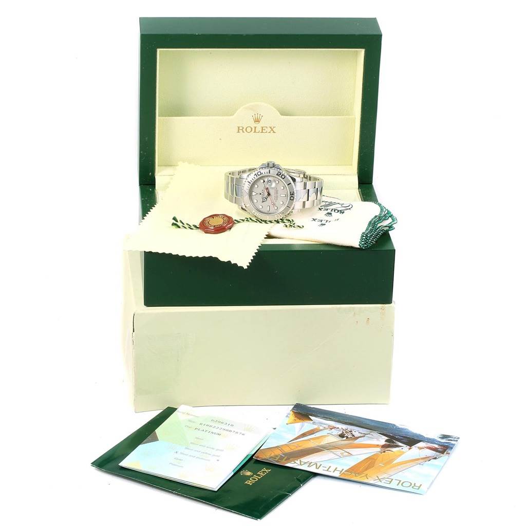 The Rolex Yacht-Master 16622 Men's Stainless Steel Silver Dial 16622 Men's Stainless Steel Silver Dial watch is shown in its open case, along with booklets, tags, and a cloth at a frontal angle.