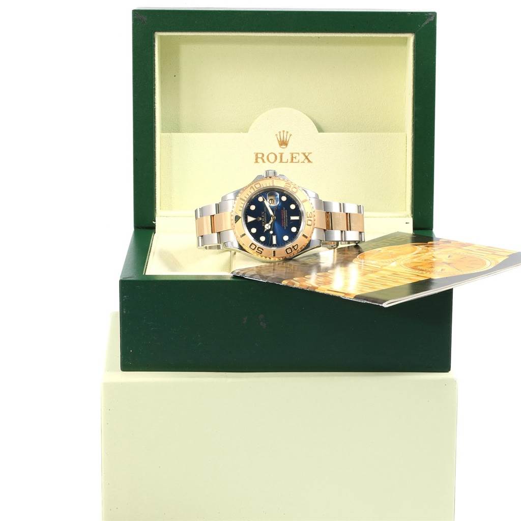 The Rolex Yacht-Master 16623 Men's Stainless Steel Blue Dial 16623 Men's Stainless Steel Blue Dial watch is displayed at a front angle inside its green and beige box, accompanied by its manual.