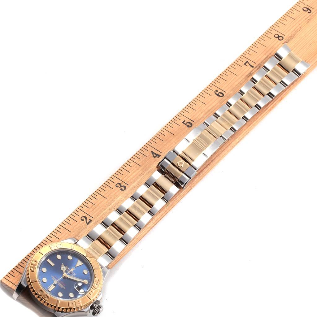 The image shows a Rolex Yacht-Master 168623 Men's Steel and Gold (two tone) Blue Dial 168623 Men's Steel and Gold (two tone) Blue Dial watch laid flat, highlighting the face, bezel, and bracelet alongside a ruler.