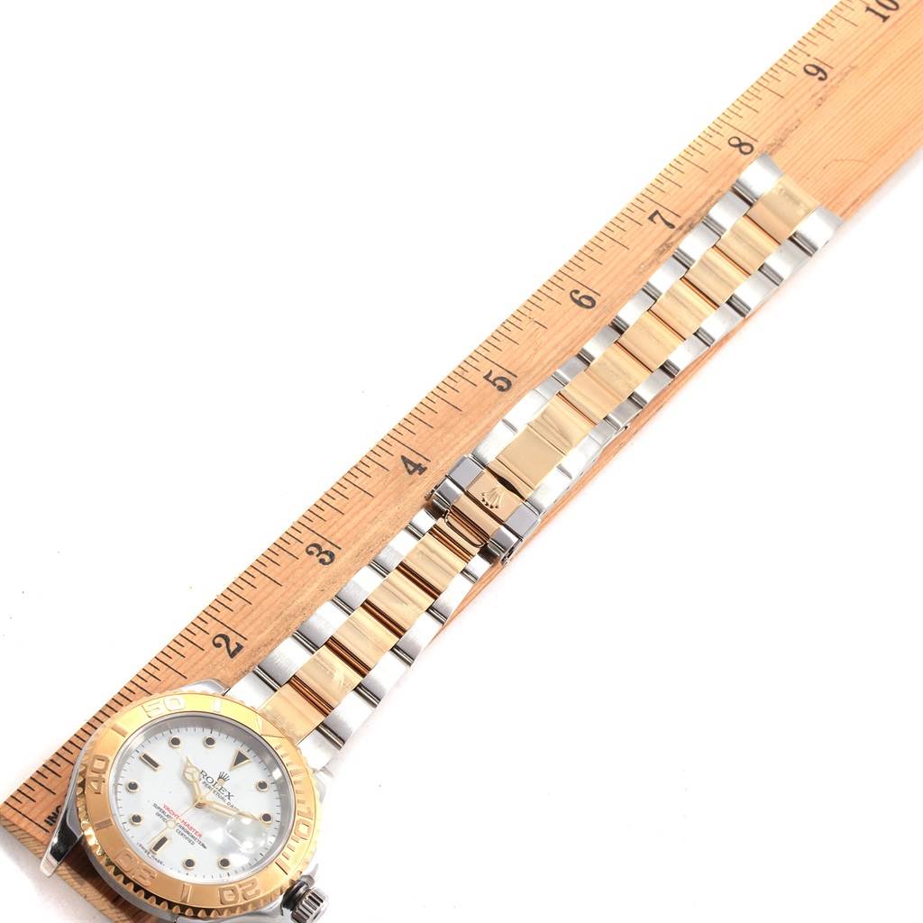 This image shows a Rolex Yacht-Master 16623 Men's Stainless Steel White Dial 16623 Men's Stainless Steel White Dial watch face down with its bracelet extended alongside a wooden ruler.
