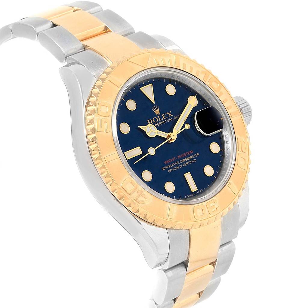 The image shows a tilted view of a Rolex Yacht-Master 16623 Men's Stainless Steel Blue Dial 16623 Men's Stainless Steel Blue Dial watch, highlighting its blue dial, gold bezel, and two-tone bracelet.