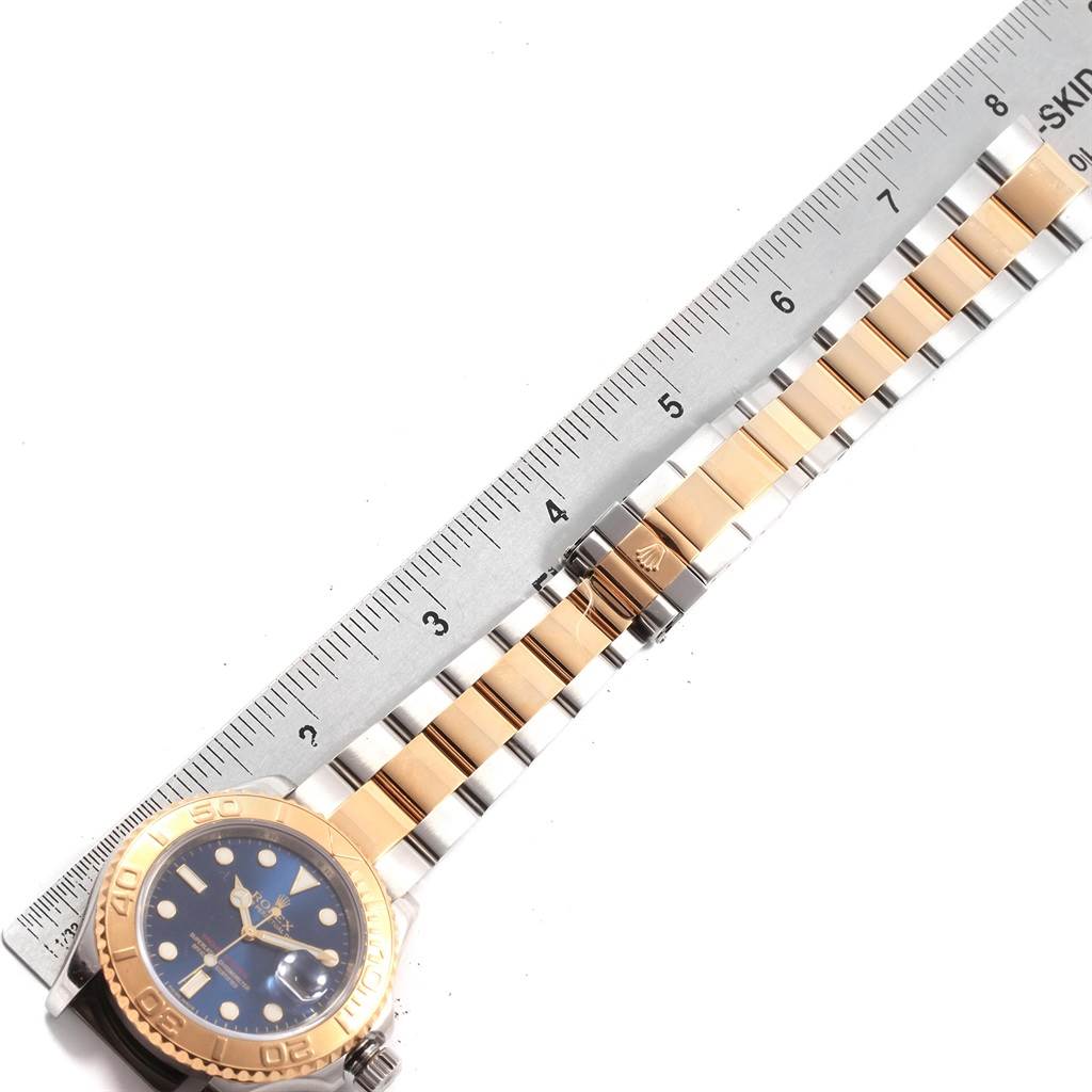 This is a top-down view of a Rolex Yacht-Master 16623 Men's Stainless Steel Blue Dial 16623 Men's Stainless Steel Blue Dial watch, showing the face, bezel, and part of the bracelet alongside a ruler.