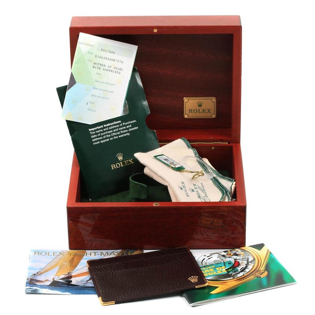 This image shows the accessories and documents for a Rolex Yacht-Master 16628 Men's Yellow Gold Mother of Pearl Dial 16628 Men's Yellow Gold Mother of Pearl Dial watch, including a box, manuals, and a guarantee card.