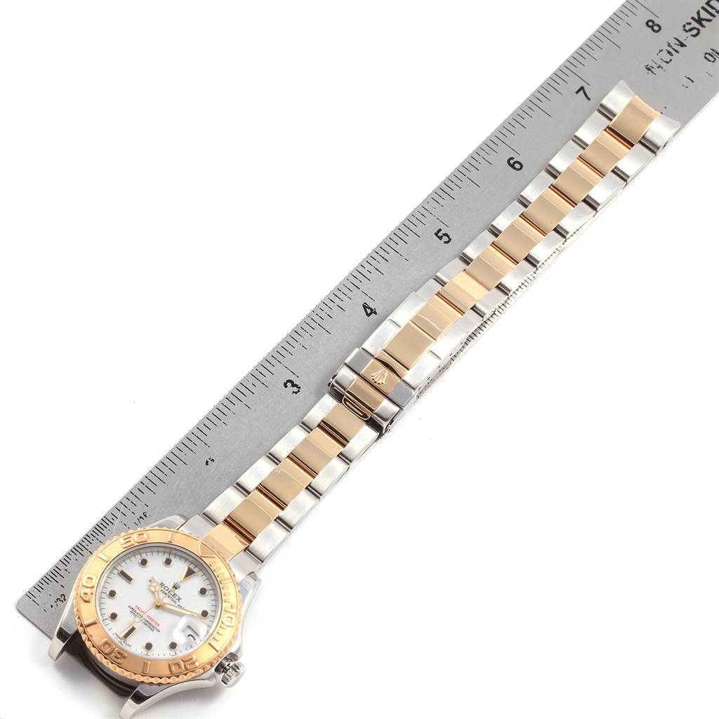 The image shows a top view of a Rolex Yacht-Master 168623 Men
s Steel and Gold (two tone) White Dial 168623 Men
s Steel and Gold (two tone) White Dial watch with a two-tone metal bracelet next to a ruler.