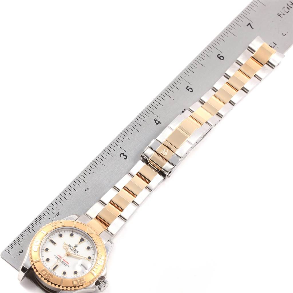 The Rolex Yacht-Master 168623 Men's Steel and Gold (two tone) White Dial 168623 Men's Steel and Gold (two tone) White Dial watch is shown from a top-down angle alongside a ruler, highlighting the full band and bezel.