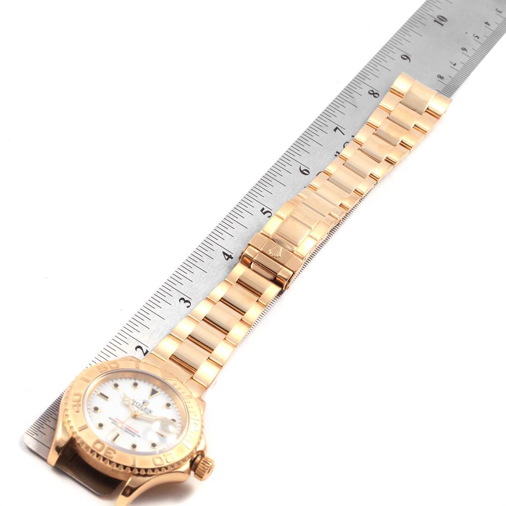 The Rolex Yacht-Master 16628 Men's Yellow Gold White Dial 16628 Men's Yellow Gold White Dial watch is shown from an overhead angle with the bracelet laid next to a ruler.