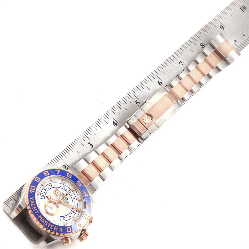 The image shows a Rolex Yacht-Master 116681 Men
s Steel and Gold (two tone) White Dial 116681 Men
s Steel and Gold (two tone) White Dial watch angled to display its face, band, and part of a ruler for size reference.