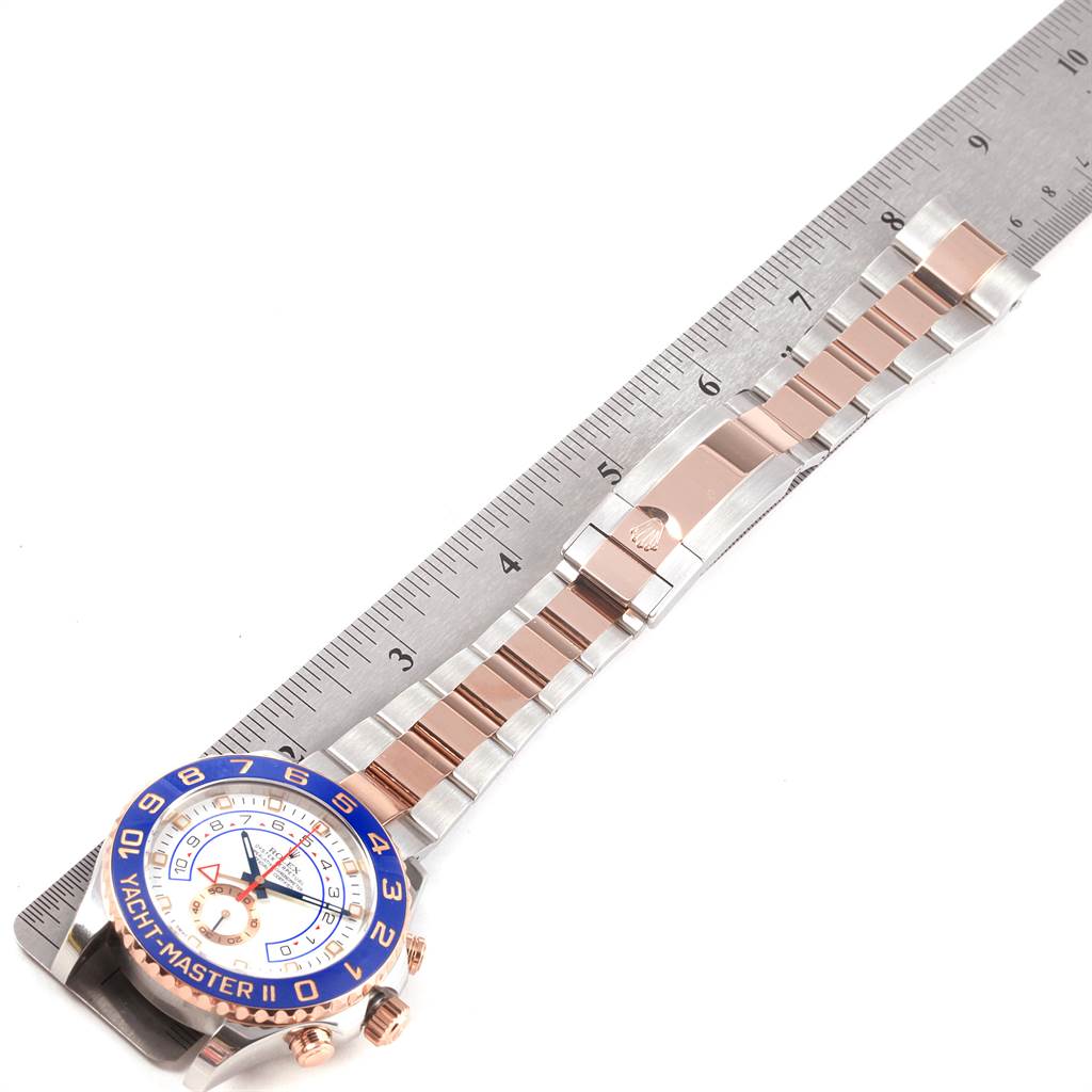 The image shows a Rolex Yacht-Master 116681 Men
s Steel and Gold (two tone) White Dial 116681 Men
s Steel and Gold (two tone) White Dial watch, partially measured against a ruler, displaying the face, bezel, band, and clasp.