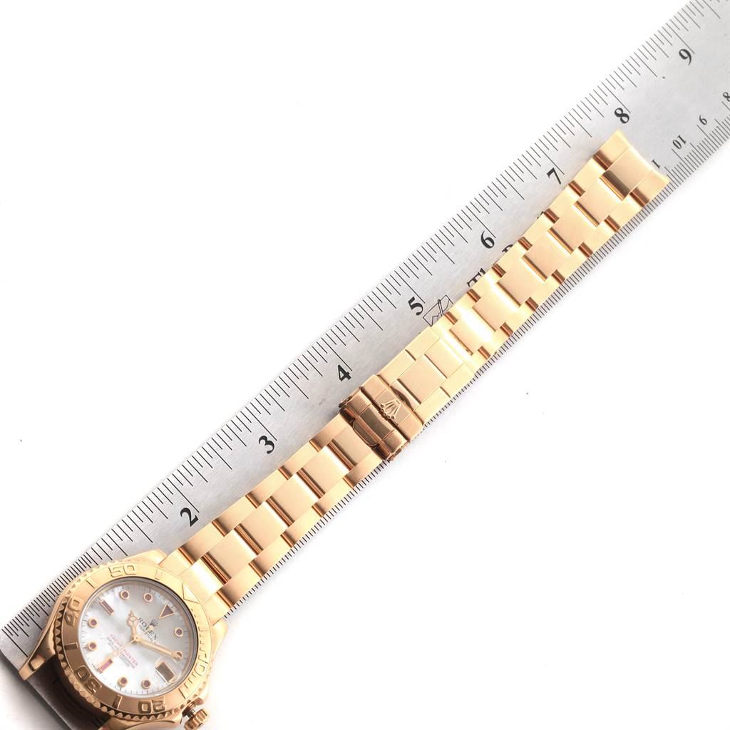 The image shows a Rolex Yacht-Master 68628 Men
s Yellow Gold Mother of Pearl Dial 68628 Men
s Yellow Gold Mother of Pearl Dial watch laid flat, displaying the bracelet and clasp next to a ruler for measurement.