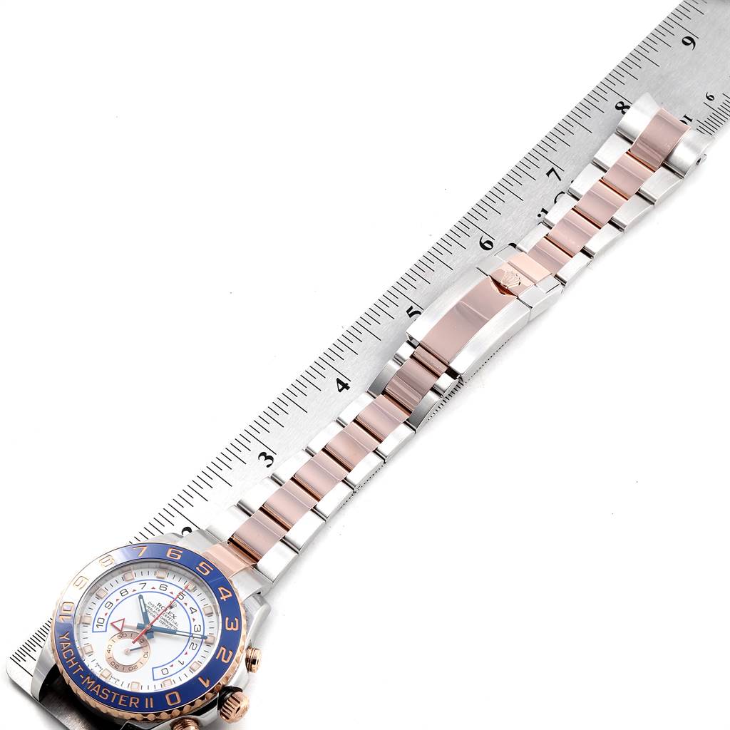 The Rolex Yacht-Master 116681 Men
s Steel and Gold (two tone) White Dial 116681 Men
s Steel and Gold (two tone) White Dial watch is shown from an aerial view, highlighting the face, bezel, and band against a ruler for size reference.