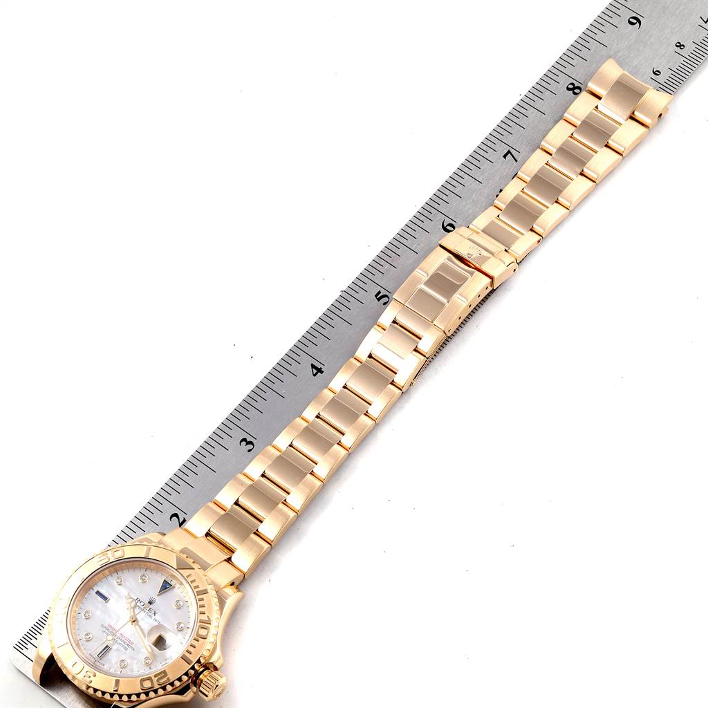 A Rolex Yacht-Master 16628 Men
s Yellow Gold Mother of Pearl Dial 16628 Men
s Yellow Gold Mother of Pearl Dial watch is shown, displaying its gold bracelet, clasp, and part of the dial with a ruler for scale.