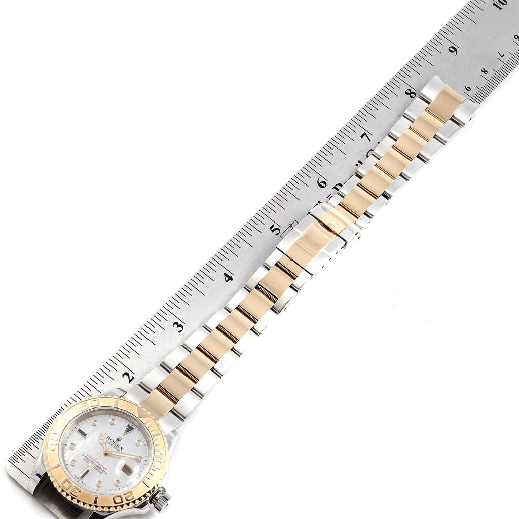 The Rolex Yacht-Master 16623 Men's Stainless Steel Mother of Pearl Dial 16623 Men's Stainless Steel Mother of Pearl Dial watch is photographed from above, showing its face, bezel, and full bracelet laid next to a ruler.