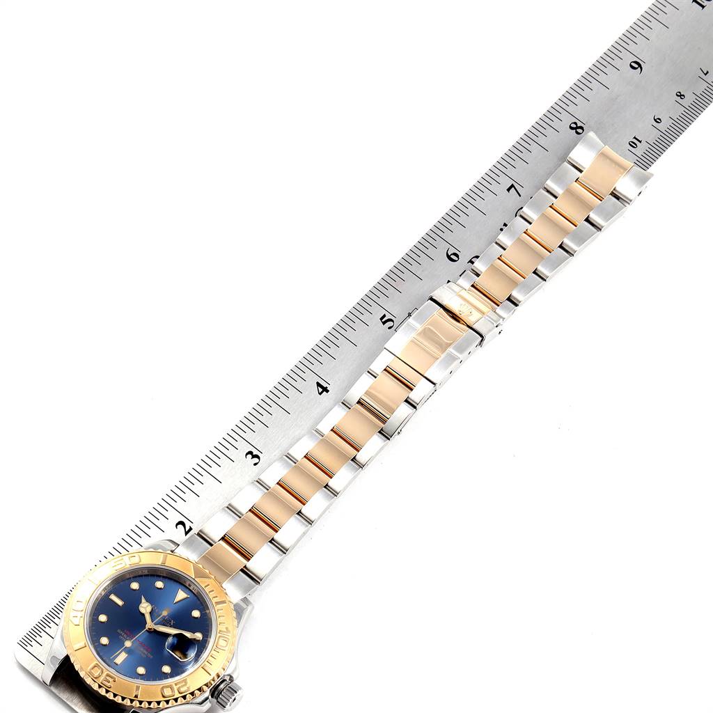 The Rolex Yacht-Master 16623 Men's Stainless Steel Blue Dial 16623 Men's Stainless Steel Blue Dial watch is shown from a top-down angle alongside a ruler, highlighting its band and face.