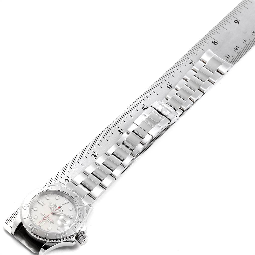 The Rolex Yacht-Master 16622 Men
s Stainless Steel Silver Dial 16622 Men
s Stainless Steel Silver Dial watch is shown from a top-down angle, featuring its face, bezel, crown, and bracelet alongside a ruler.