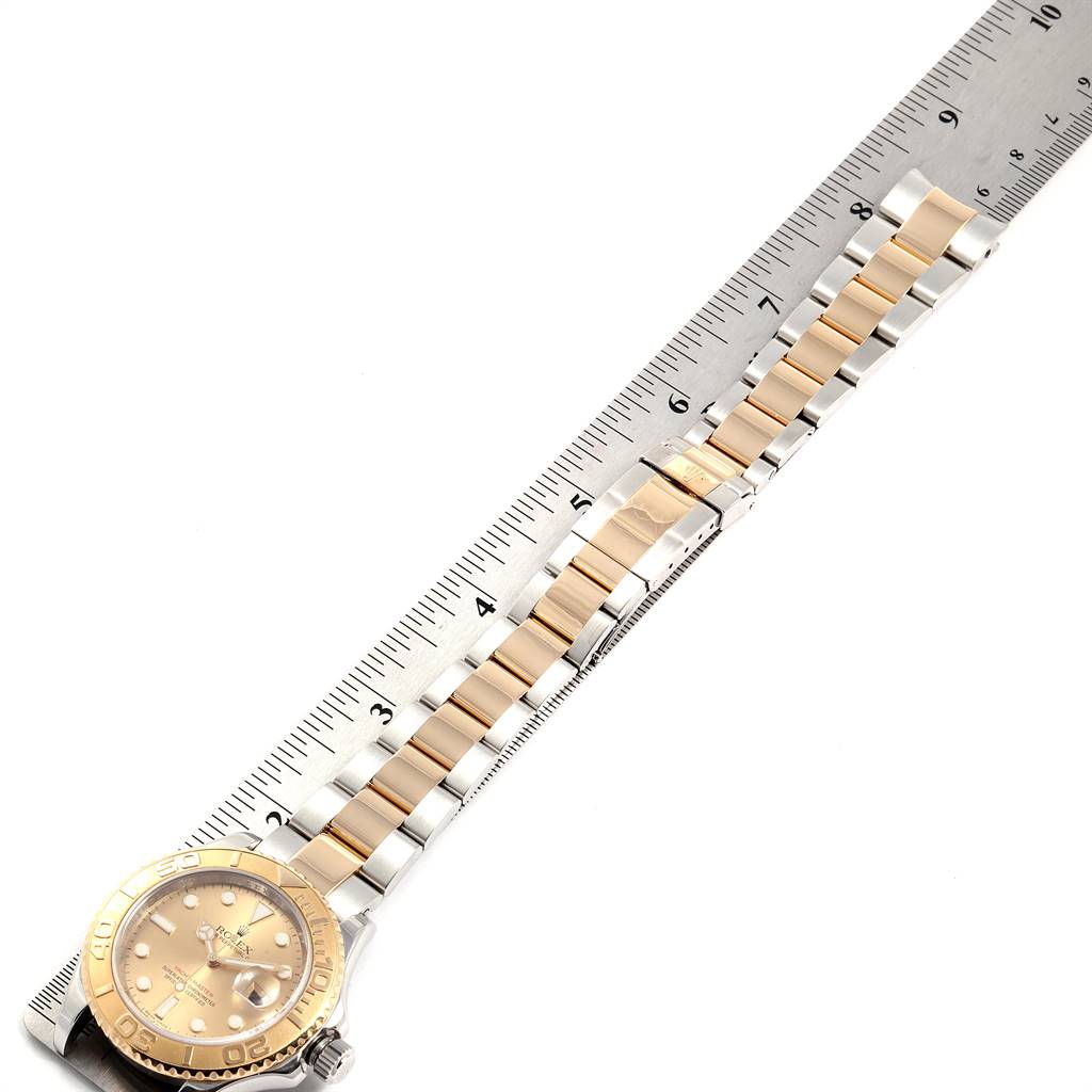 The image shows a gold and silver Rolex Yacht-Master 16623 Men's Stainless Steel Champagne Dial 16623 Men's Stainless Steel Champagne Dial watch laying flat with a metal ruler alongside it to measure its length.