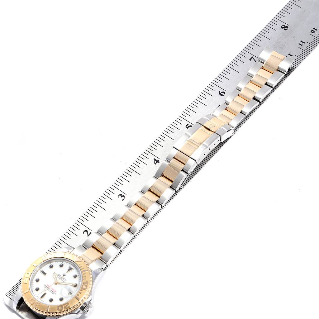 This image shows the Rolex Yacht-Master 168623 Men's Steel and Gold (two tone) White Dial 168623 Men's Steel and Gold (two tone) White Dial watch laid flat next to a ruler, displaying the entire band and face from an overhead angle.
