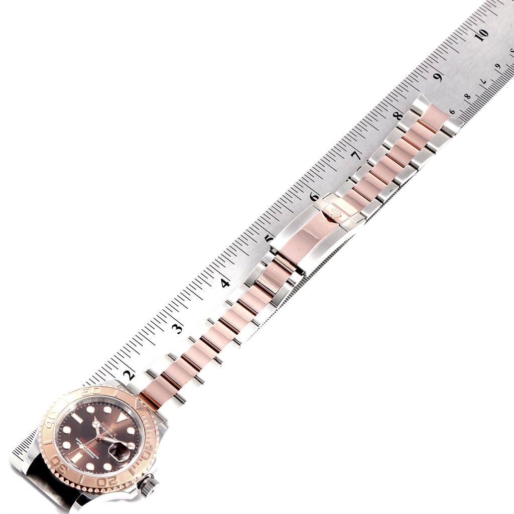 The Rolex Yacht-Master 116621 Men's Stainless Steel Brown Dial 116621 Men's Stainless Steel Brown Dial watch is shown laid flat against a ruler, highlighting the bezel, dial, and bracelet.