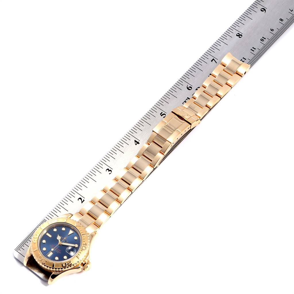 The image shows a gold Rolex Yacht-Master 68628 Yellow Gold Blue Dial 68628 Yellow Gold Blue Dial watch with a blue dial, laid next to a ruler for measurement.